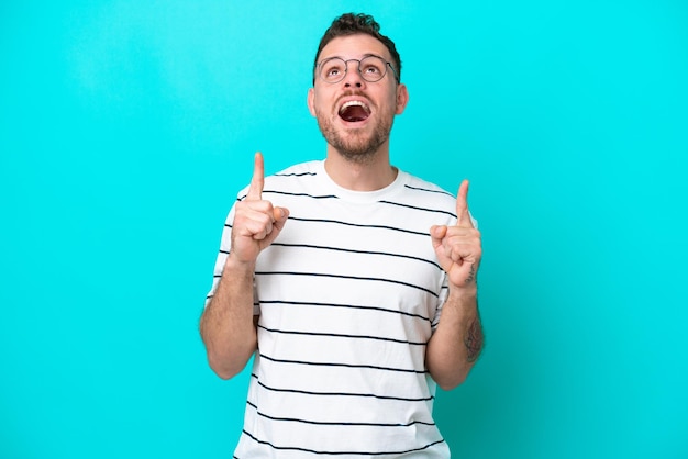 Young Brazilian man isolated on blue background surprised and pointing up