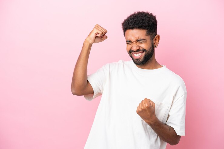 Photo young brazilian man isolated on pink background celebrating a victory