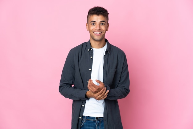 Young Brazilian man isolated on pink background laughing
