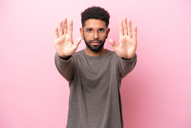 Young Brazilian man isolated on pink background making stop gesture and disappointed