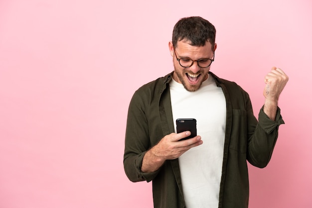 Young Brazilian man isolated on pink background surprised and sending a message