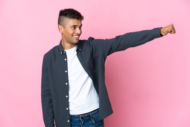 Young Brazilian man isolated on pink space giving a thumbs up gesture