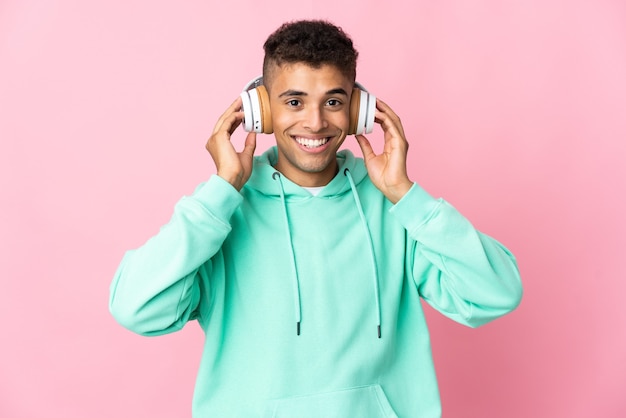 Young Brazilian man over isolated wall listening music