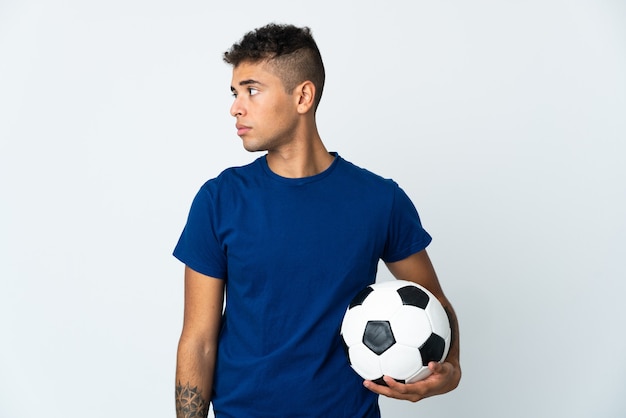 Young Brazilian man over isolated wall with soccer ball