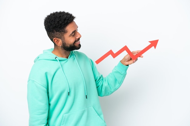 Young Brazilian man isolated on white background holding a catching a rising arrow with happy expression