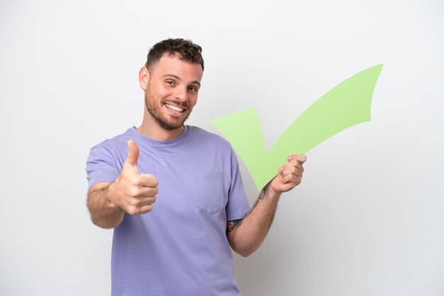 Young Brazilian man isolated on white background holding a check icon with thumb up