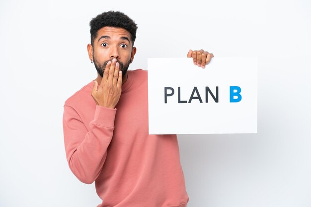 Young Brazilian man isolated on white background holding a placard with the message PLAN B with surprised expression