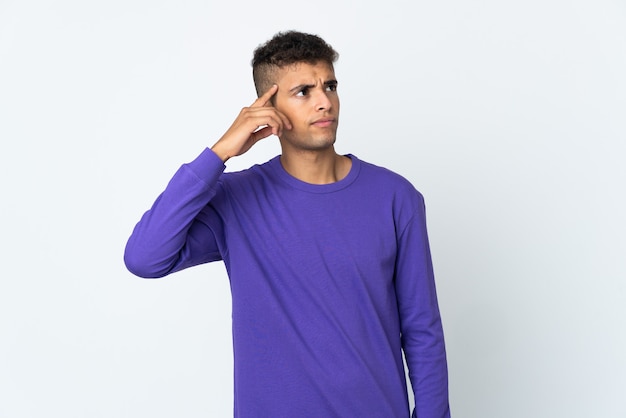 Young brazilian man isolated on white background making the gesture of madness putting finger on the head