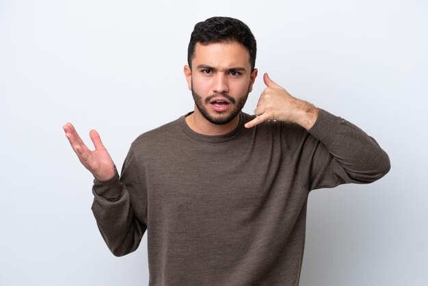 Photo young brazilian man isolated on white background making phone gesture and doubting