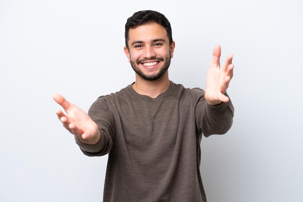 Young Brazilian man isolated on white background presenting and inviting to come with hand