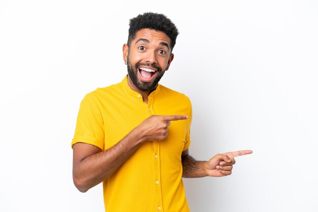 Young Brazilian man isolated on white background surprised and pointing side