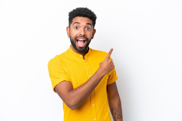 Young Brazilian man isolated on white background surprised and pointing side