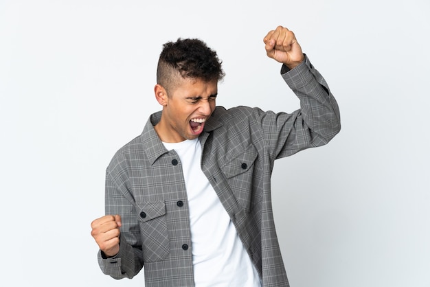 Young brazilian man isolated on white wall celebrating a victory