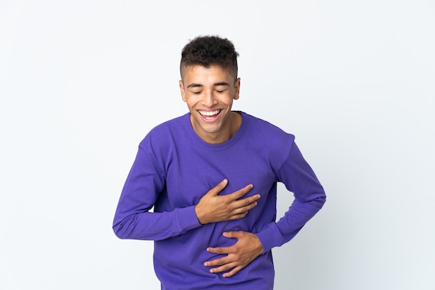 Young brazilian man isolated on white wall smiling a lot