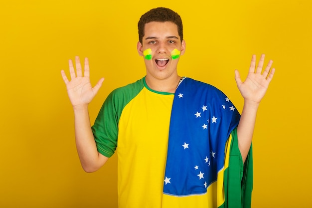 Young brazilian man soccer fan dressed in green surprised by the flag of brazil