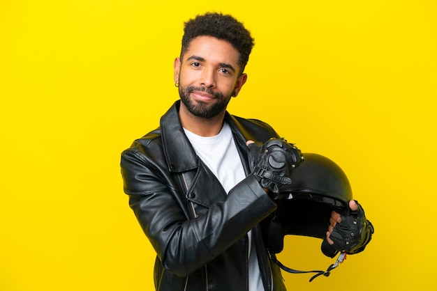 Young brazilian man with a motorcycle helmet isolated on yellow background proud and selfsatisfied