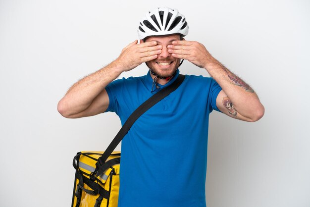 young brazilian man with thermal backpack isolated on white background covering eyes by hands