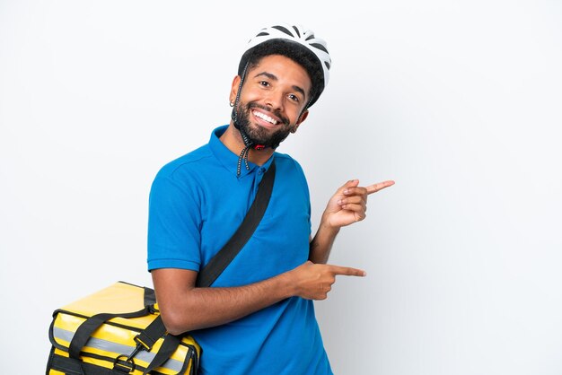 Young Brazilian man with thermal backpack isolated on white background surprised and pointing side