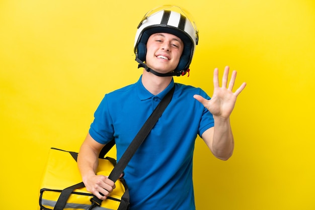 Young Brazilian man with thermal backpack isolated on yellow background counting five with fingers
