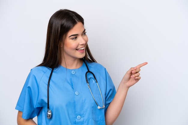 Молодая бразильская медсестра, изолированная на белом фоне, показывает пальцем в сторону и представляет продукт