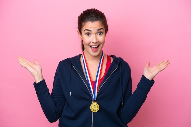 Young Brazilian sport woman with medals isolated on pink background with shocked facial expression