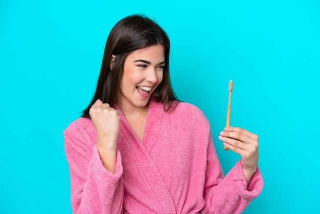 Young Brazilian woman brushing teeth isolated on blue background celebrating a victory