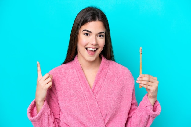 Young Brazilian woman brushing teeth isolated on blue background pointing up a great idea