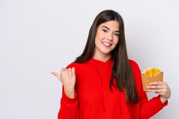 Young Brazilian woman catching french fries isolated on white background pointing to the side to present a product