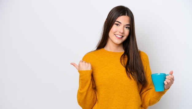 Young Brazilian woman holding cup of coffee isolated on white background pointing to the side to present a product