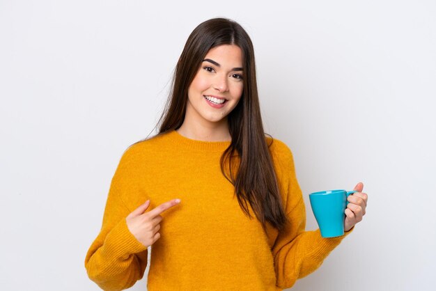 Young Brazilian woman holding cup of coffee isolated on white background with surprise facial expression