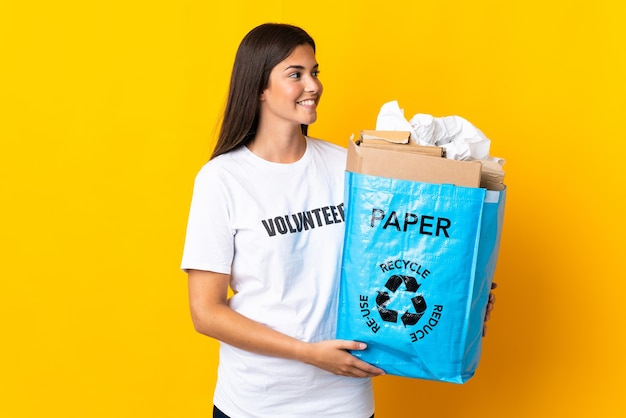 Young brazilian woman holding a recycling bag full of paper to recycle isolated