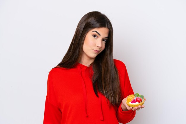 Young Brazilian woman holding a tartlet isolated on white background with sad expression