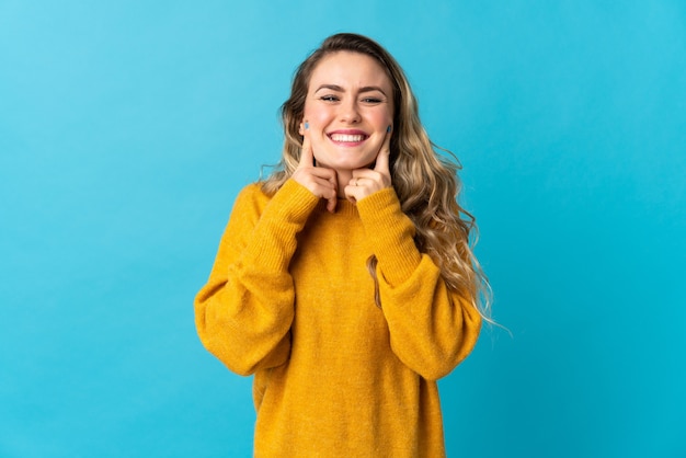 Young Brazilian woman isolated on blue smiling with a happy and pleasant expression