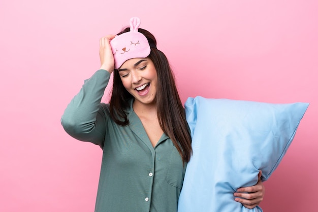 Young Brazilian woman isolated on pink background in pajamas and intending the solution