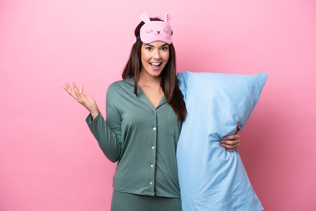 Young Brazilian woman isolated on pink background in pajamas and with shocked facial expression