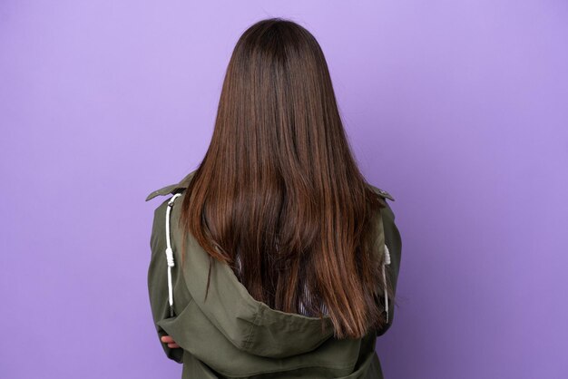 Young brazilian woman isolated on purple background in back position