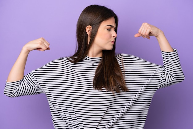 Young Brazilian woman isolated on purple background doing strong gesture