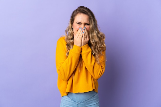 Young Brazilian woman isolated on purple background happy and smiling covering mouth with hands