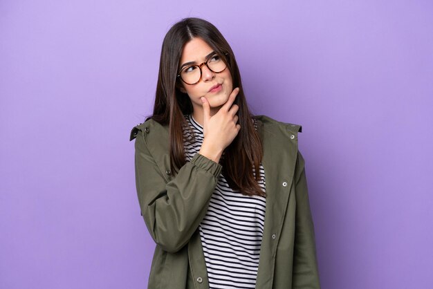 Young Brazilian woman isolated on purple background having doubts