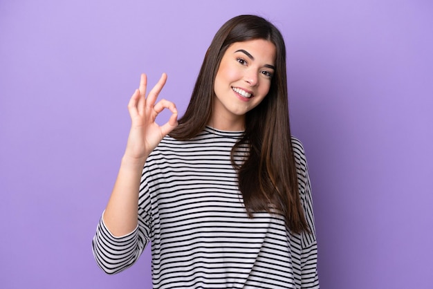 Young brazilian woman isolated on purple background showing ok sign with fingers