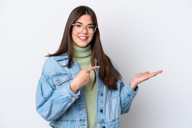 Young Brazilian woman isolated on white background holding copyspace imaginary on the palm to insert an ad