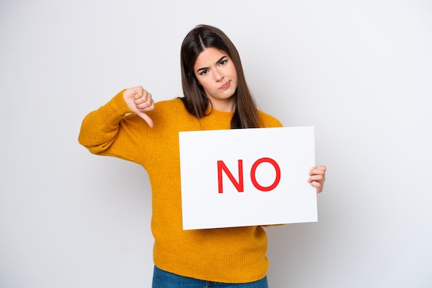 Young Brazilian woman isolated on white background holding a placard with text NO