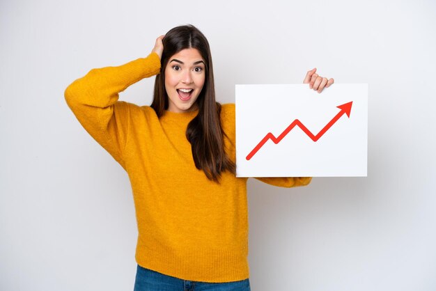 Young Brazilian woman isolated on white background holding a sign with a growing statistics arrow symbol with surprised expression