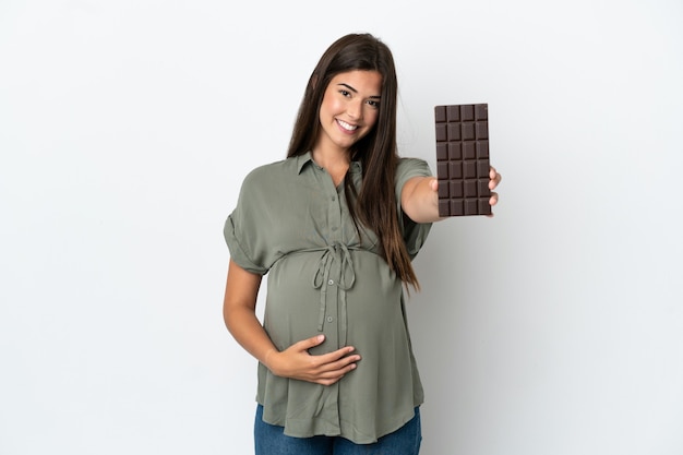 Молодая бразильская женщина изолирована на белом фоне беременной и держит шоколад