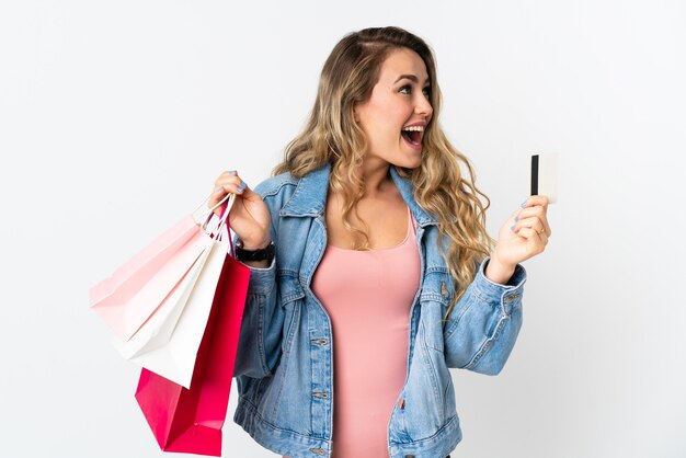 Young Brazilian woman isolated on white  holding shopping bags and a credit card