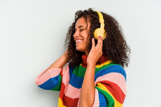 Young brazilian woman listening to music isolated on blue background