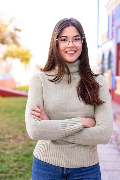 Young Brazilian woman at outdoors With glasses with happy expression