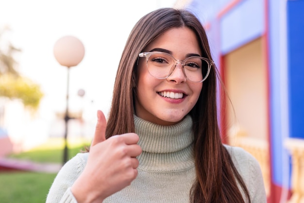 屋外で眼鏡をかけ、親指を立てた若いブラジル人女性