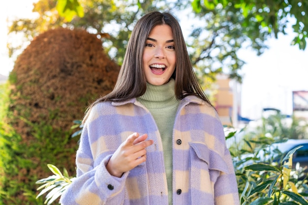 Young Brazilian woman in a park surprised and pointing front