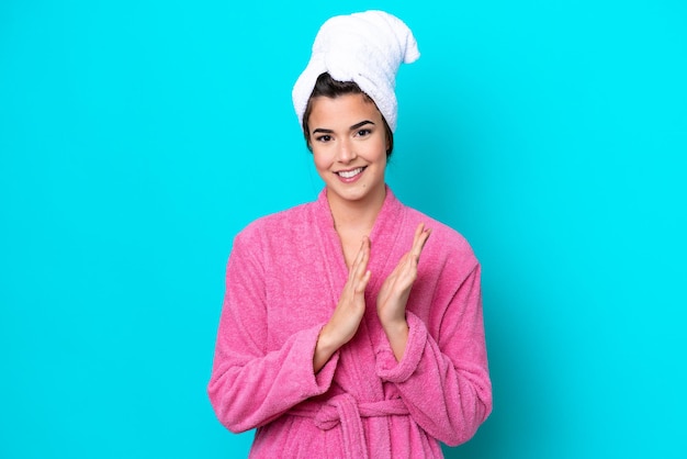 Young Brazilian woman with a bathrobe isolated on blue background applauding after presentation in a conference